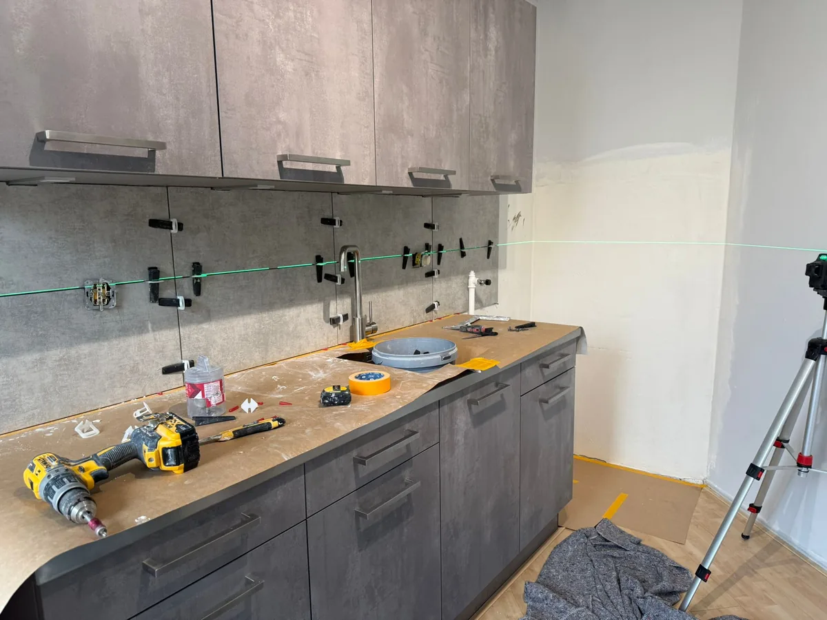 Betegelde spatwand in betonlook achter het aanrecht van een keuken in Waldeck, Den Haag
