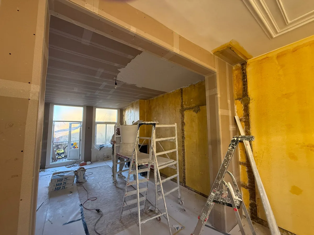 Woonkamer aan de Piet Heinstraat in Den Haag voor het stucwerk, met oude gele wanden