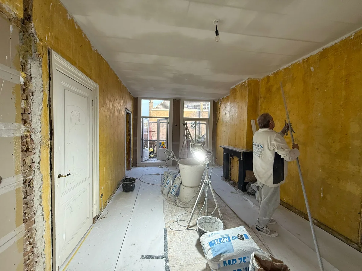 Stukadoor van Stukadoorsbedrijf Egaal werkt de wand af in de woonkamer aan de Piet Heinstraat