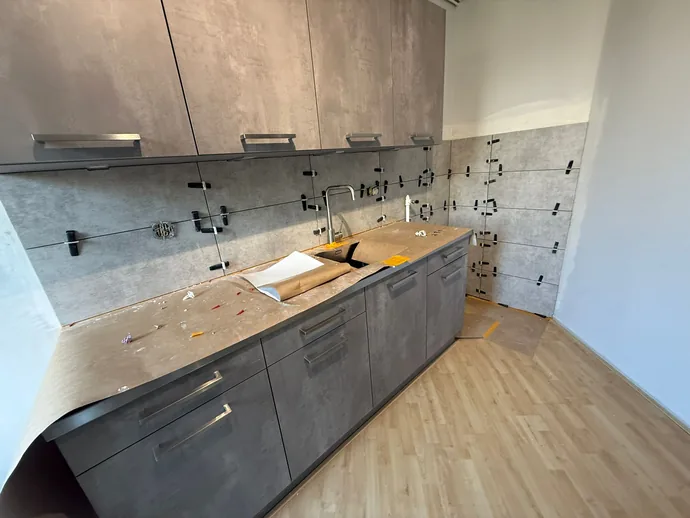Betegelde spatwand in betonlook achter het aanrecht van een keuken in Waldeck, Den Haag